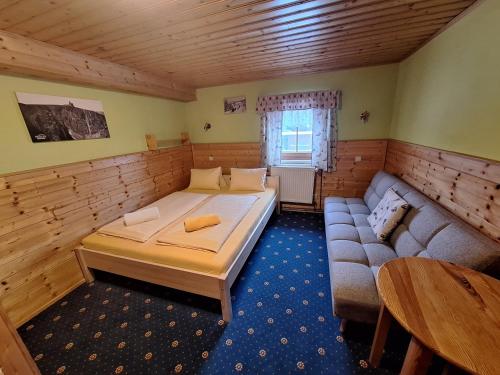 a room with a bed and a couch and a table at Pomezní bouda in Horní Malá Úpa