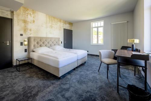 a bedroom with a bed and a desk and a piano at Hotel Villa Hirzel in Schwäbisch Gmünd
