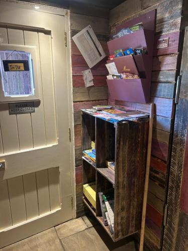 a book shelf next to a door with books at Rhodes To Serenity - Waterfall Shepherds Hut in Cauldon