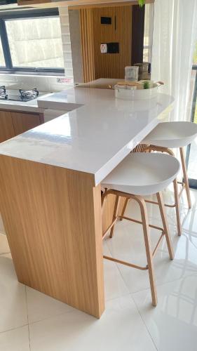 a kitchen with a white counter and some chairs at Villa Dwikora Pekanbaru in Pekanbaru