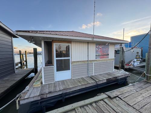 a small building on a dock next to the water at The Miss Ella Houseboat 