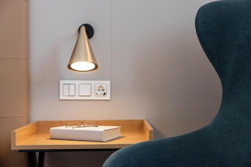a table with a book and a lamp and a chair at Senator Cádiz in Cádiz