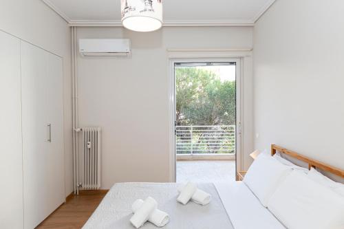 a white bedroom with a bed and a window at The Glyfada Hideaway in Athens