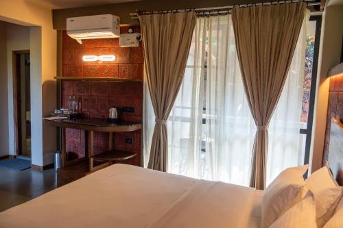 a bedroom with a bed and a desk and a window at Villa Katipadu Coorg in Srimangala