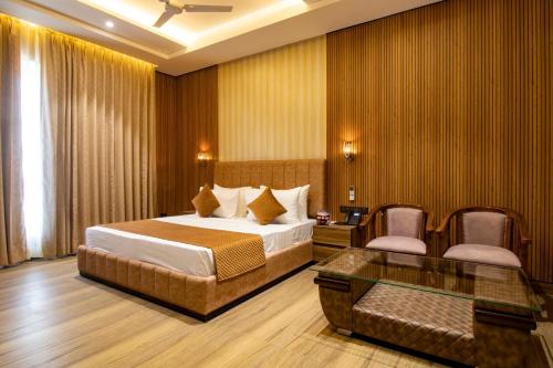 a hotel room with a bed and a glass table at The Velvista Hotel in Muzaffarnagar