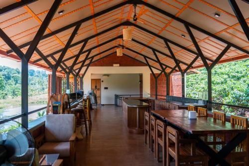 a dining room with wooden ceilings and tables and chairs at Villa Katipadu Coorg in Srimangala