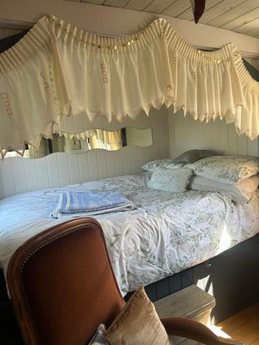 ein Bett in einem Zimmer mit einem Fenster und einem Stuhl in der Unterkunft Rhodes To Serenity - Showmans Van in Cauldon