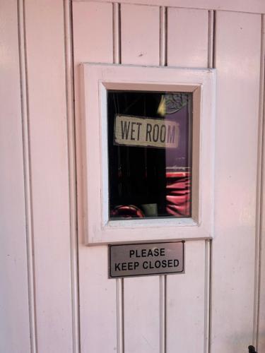 a window in a door with a sign that reads wet room at Rhodes To Serenity - Showmans Van in Cauldon