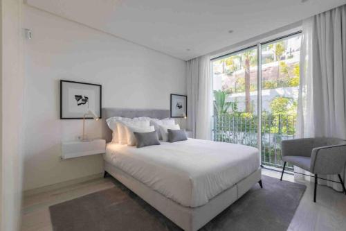 a white bedroom with a bed and a window at 812 ALM Luxury aparment in Palo Alto, Marbella in Ojén
