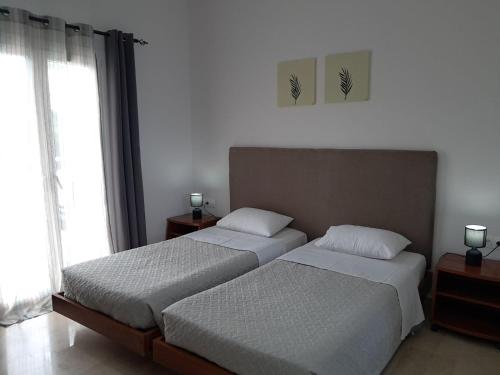 two beds in a room with two windows at Kosmas Apartments in Roda