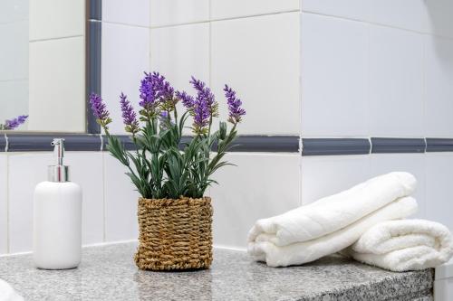 eine Vase mit lila Blumen auf einer Theke im Bad in der Unterkunft Holiday Praia da Rocha in Strand Praia da Rocha