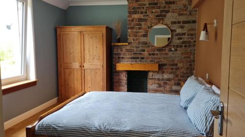 a bedroom with a bed and a brick wall at Forest View Guesthouse, Kinlochleven WHW in Kinlochmore