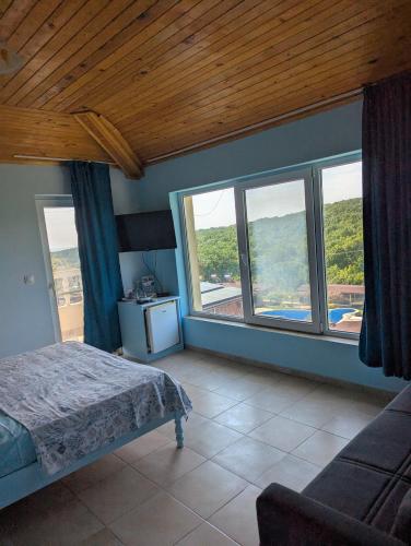 a bedroom with a bed and large windows at Guest House Chalakov in Sinemorets