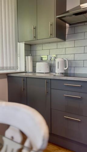 a kitchen with gray cabinets and white appliances at Spacious 2 Bedroom Flat City Centre in Cannock