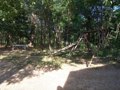 un parc avec une balançoire dans les bois dans l'établissement Huswell - Rustic Gite with Pool in Southern France, à Saint-Ambroix