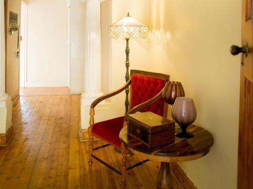 a room with a red chair and a table with a lamp at Nobis House Annex in Bloemfontein