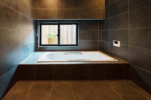 a bath tub in a bathroom with a window at 町宿 紬 in Obama