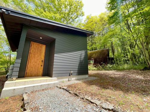 a small house with a wooden door in the woods at Narusawa MADOKA in Wada