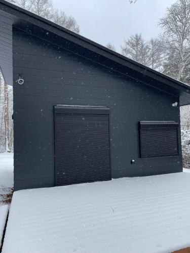 a building with two garage doors in the snow at Narusawa MADOKA in Wada