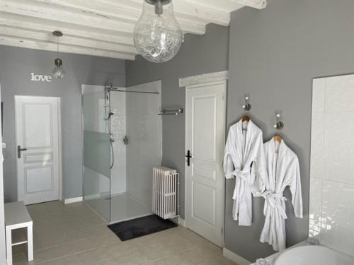 a bathroom with white robes hanging on the wall at SUITE ROMANTIQUe in Cléré-les-Pins