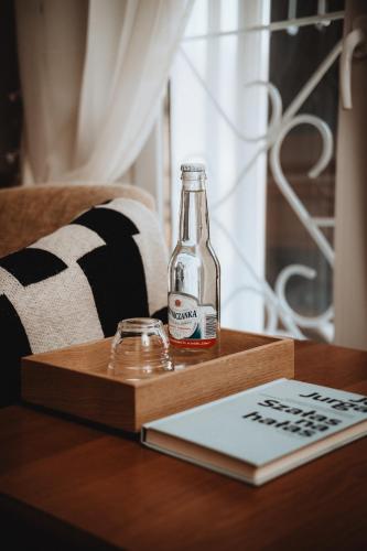 a bottle of alcohol on a wooden table with a book at Pensjonat Witoldówka in Krynica Zdrój
