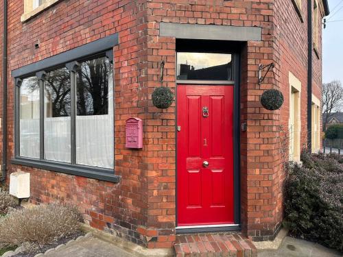 a red door on the side of a brick building at NEW Victorian Residence - sleeps 12 in Frome