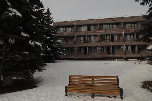 a wooden bench in the snow in front of a building at Ani Resort in Artavaz