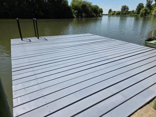 a wooden dock in the water on a lake at Szitakötő Békésszentandrás Vendégház in Békésszentandrás