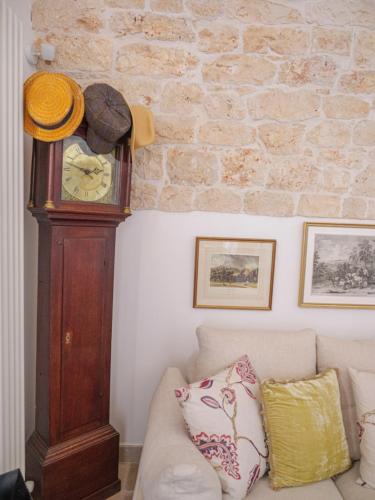 a grandfather clock in a living room with a couch at Casa Pietra Bianca Fay in Castellana Grotte