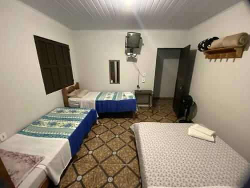um quarto com duas camas e uma TV em Pouso das Folhas em Tiradentes