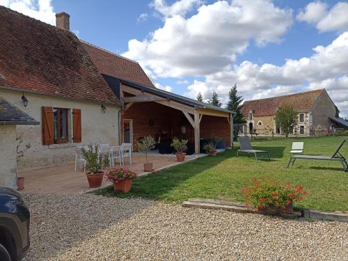 Cette maison dispose d'une terrasse et d'une cour avec des chaises. dans l'établissement Ferme de Mazerolles, à Saulnay