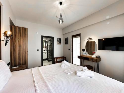 a bedroom with a large white bed with towels on it at Tinos Otel & Bağ Evi 12 Yaş Üstü in Bozcaada