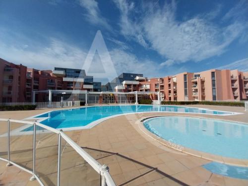 une grande piscine au milieu d'un bâtiment dans l'établissement APPARTEMENT 46M², 1 CHAMBRE, PISCINE, TENNIS, PLAGE DIRECT, à Sète