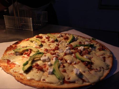 a pizza with cheese and vegetables on a table at The Wooden Spoon Guesthouse in Bethlehem