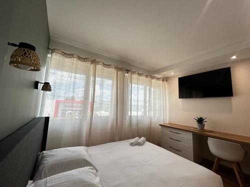 a bedroom with a bed and a desk and a television at La Suite Faïence, chic et calme in Panazol