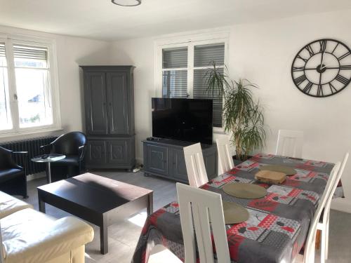 a living room with a table and a clock on the wall at 'De Maîche avec vous', 6 à 8 personnes in Maîche
