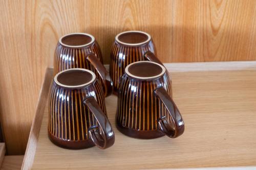 three brown vases sitting on a wooden shelf at 一棟貸し宿 松本邸 in Kinoe