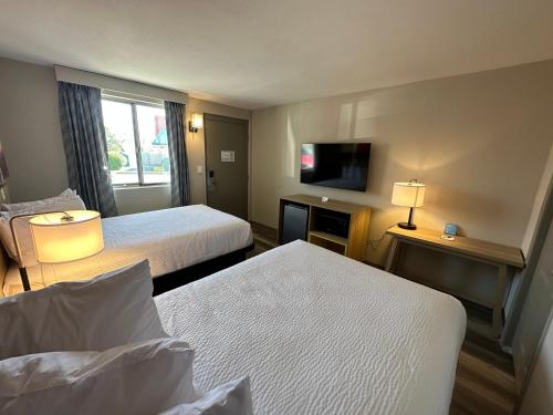 a hotel room with two beds and a flat screen tv at Days Inn by Wyndham Farmington NM in Farmington