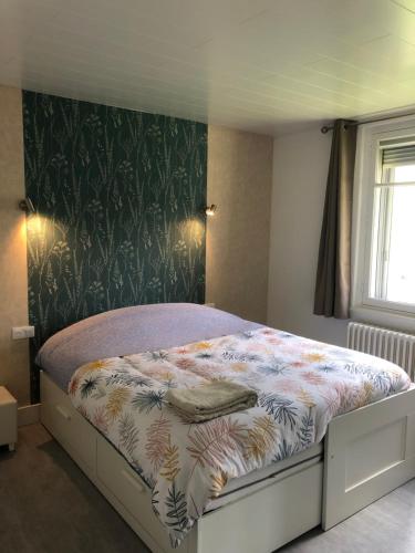 a bedroom with a bed with a floral bedspread at 'De Maîche avec vous', 6 à 8 personnes in Maîche