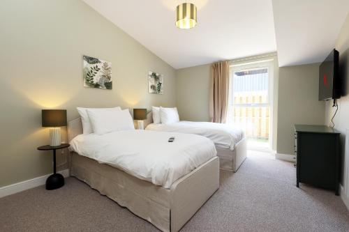 a hotel room with two beds and a television at Ground Floor Barn with Hot Tub, Dog Friendly, Sleeps up to 8 close to Monmouth, Ross on Wye, Hay on Wye and Hereford! in Broad Oak