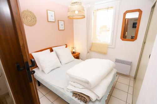 une chambre avec un lit avec des oreillers blancs et une fenêtre dans l'établissement Saint-Cyprien charmant appartement vue mer, à Saint Cyprien Plage