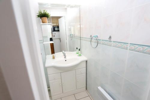 une salle de bain blanche avec un lavabo et un miroir dans l'établissement Saint-Cyprien charmant appartement vue mer, à Saint Cyprien Plage
