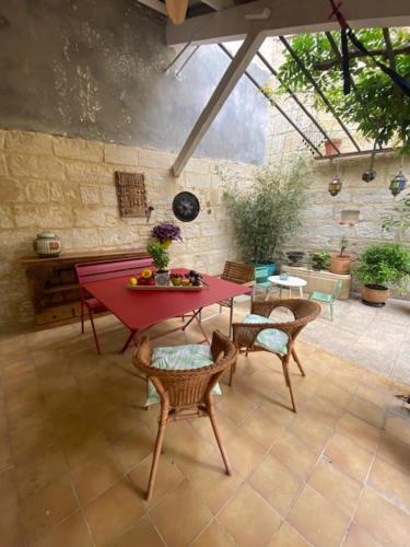 un patio avec une table et des chaises rouges dans une pièce dans l'établissement Charmante maison de village avec patio FOURQUES 10 minutes à pied d'Arles, à Fourques