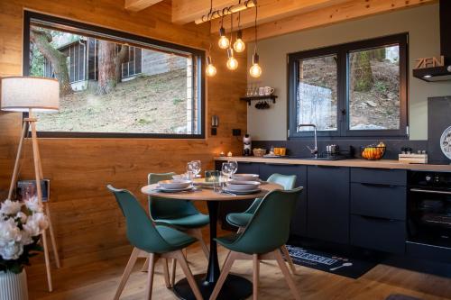 a kitchen with a table and green chairs at Les Gites du O' Forêt-Gîte O'rizon avec bain nordique et magnifique vue sur la plaine du forez in Verrières-en-Forez