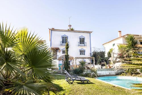 a large white house with a pool and palm trees at Santa Cruz Surf House by Stoke Travel in A dos Cunhados