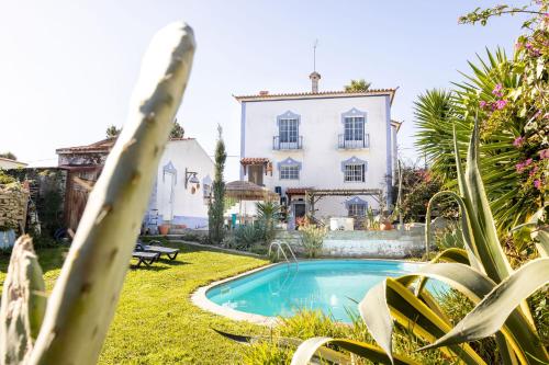 a villa with a swimming pool in front of a house at Santa Cruz Surf House by Stoke Travel in A dos Cunhados