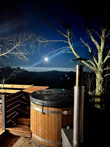 a hot tub on a deck at night at Les Gites du O' Forêt-Gîte O'rizon avec bain nordique et magnifique vue sur la plaine du forez in Verrières-en-Forez