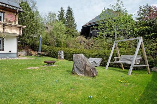 a park with a bench and a rock and a swing at Ferienwohnung am Schwellenweiher in Feldberg