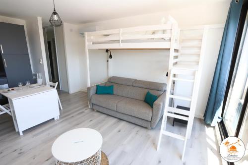 - un salon avec un canapé et des lits superposés dans l'établissement Appart lumineux et climatise St Cyprien 3 min du port, à Saint Cyprien Plage