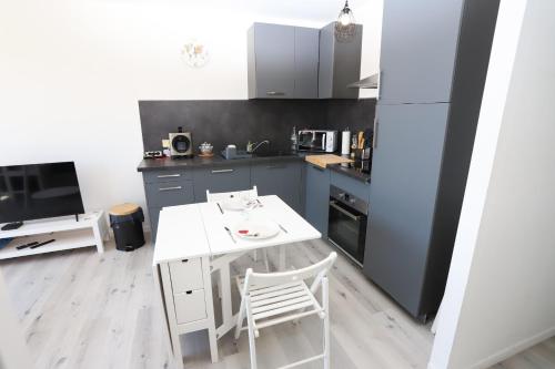 une cuisine avec une table et une chaise blanches dans l'établissement Appart lumineux et climatise St Cyprien 3 min du port, à Saint Cyprien Plage